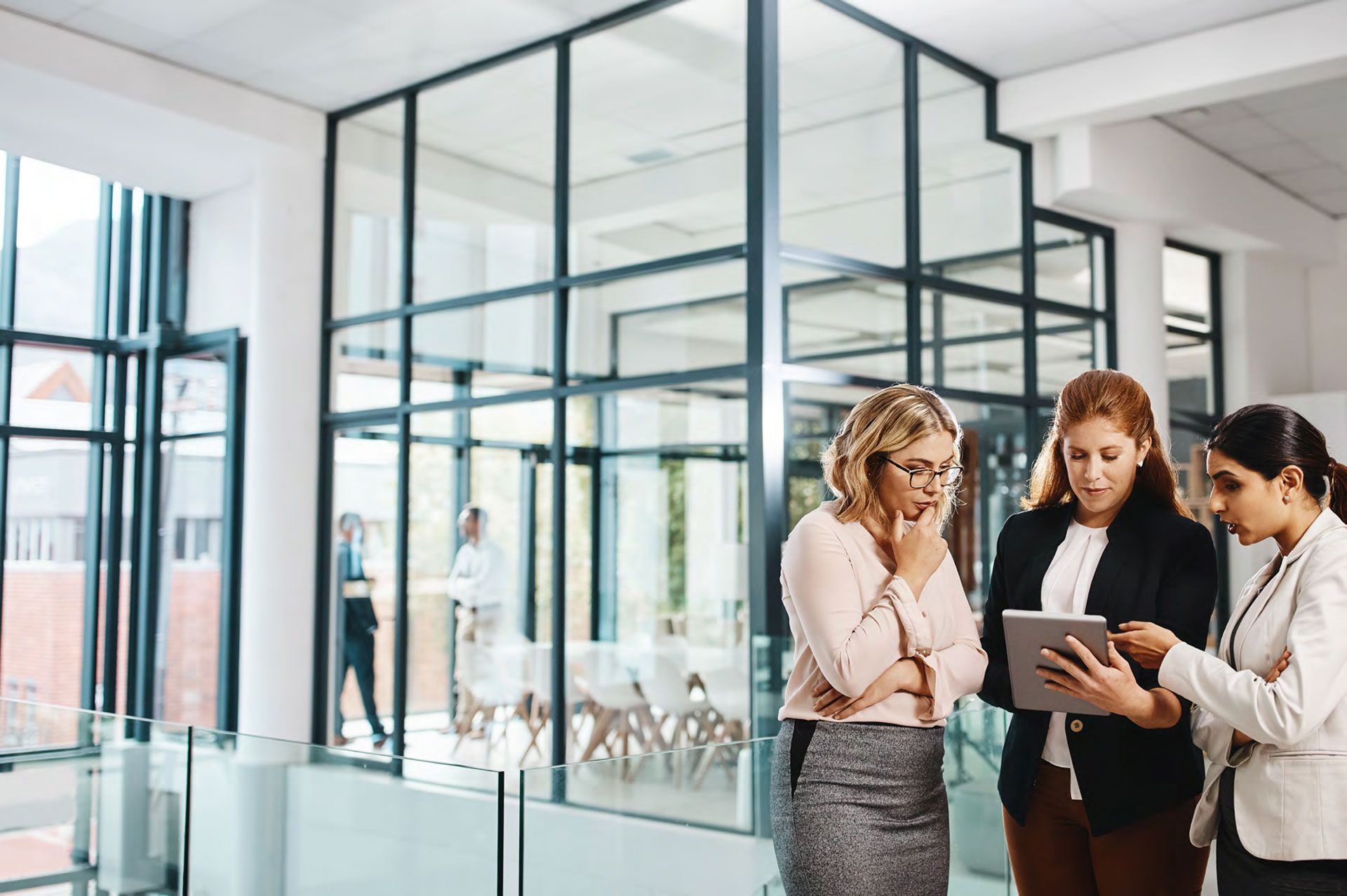 women in an office holding a touchpad